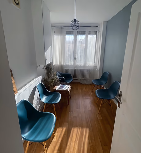 Salle d’attente avec des fauteuils bleus et une fenêtre